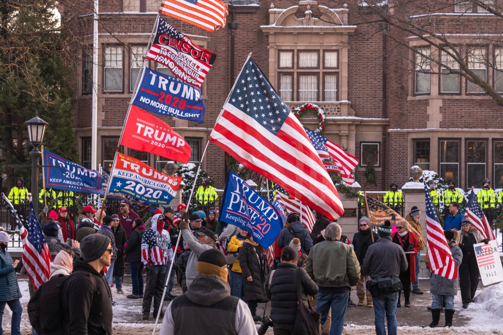 Demonstrators with Trump 2020 flags and large American flags gather in the snow outside the Minnesota Governor's Mansion at a Stop the Steal rally