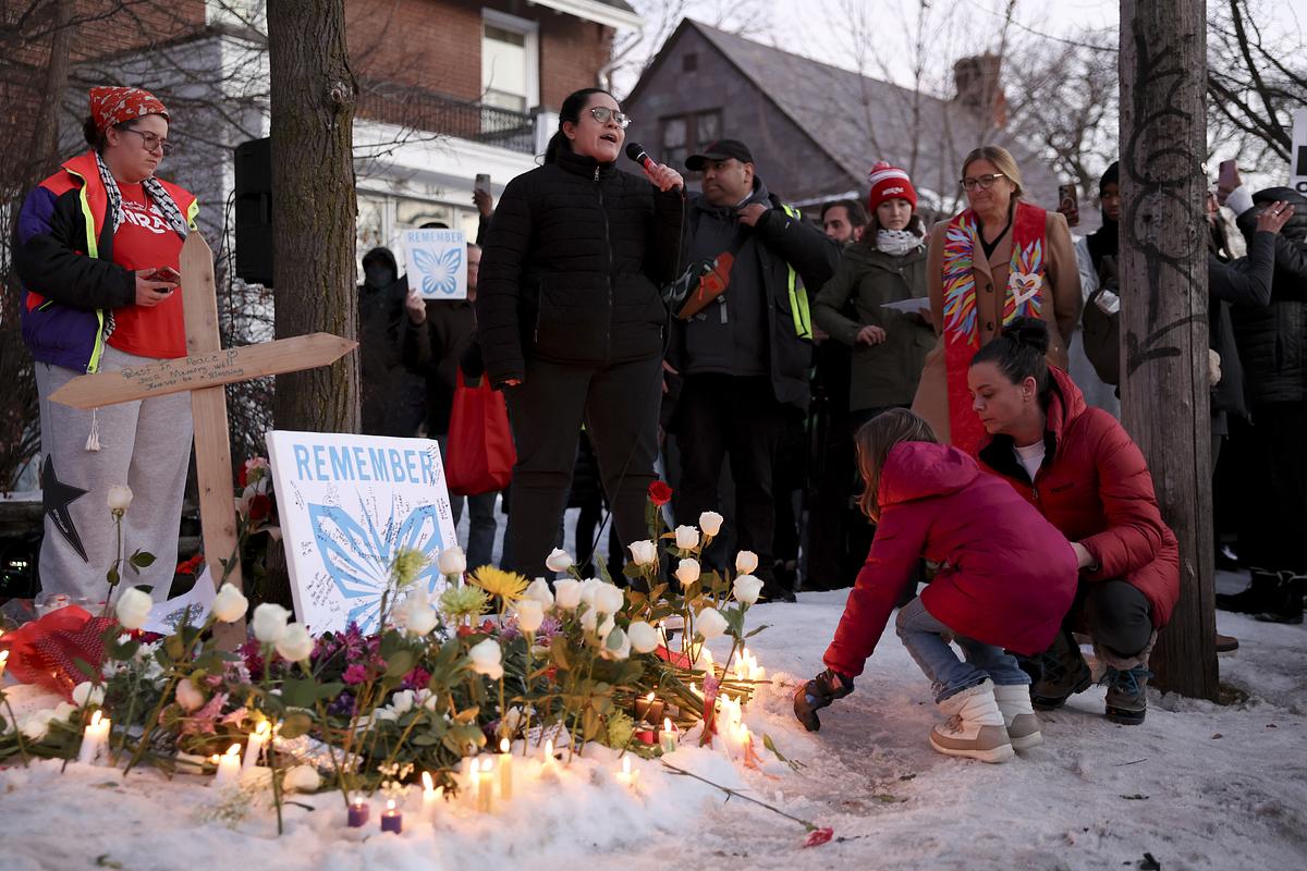 A girl places a flower at the memorial for Renee Nicole Good at 34th Street and Portland Avenue, Minneapolis
