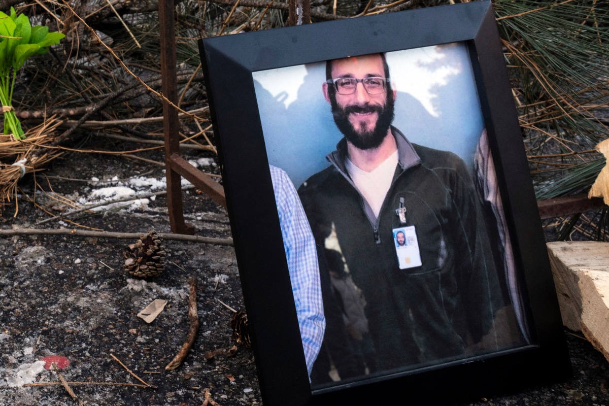 Makeshift memorial with a framed photograph, flowers, and candles at the site where Alex Pretti was killed